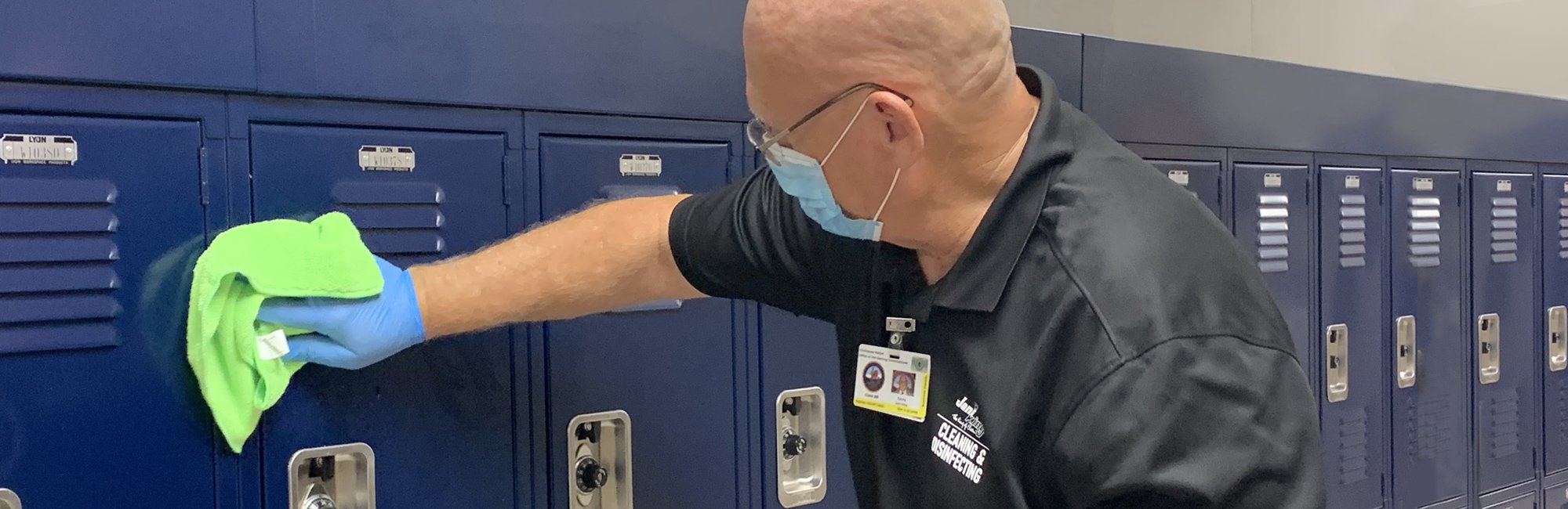 a man in a black shirt and blue gloves cleaning lockers