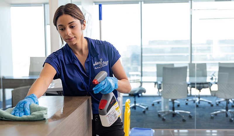 a woman cleaning a table with a spray bottle