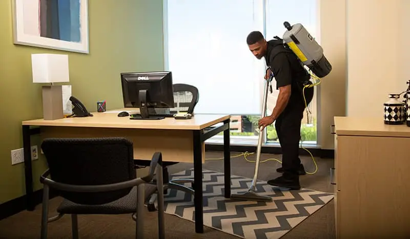 Janitor vacuuming the rug of a hotel room