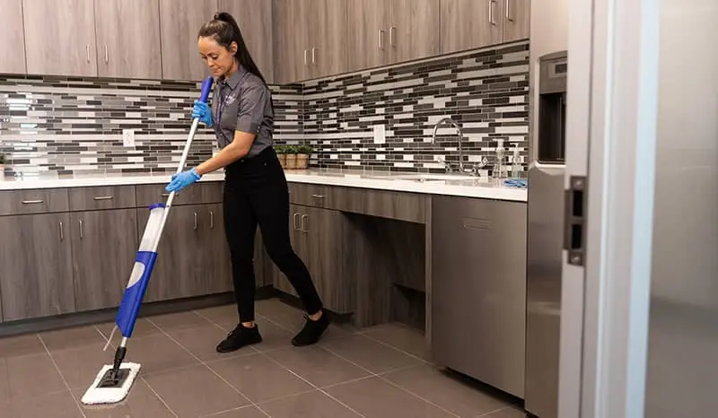 Janitorial worker mopping the floor of a workplace breakroom