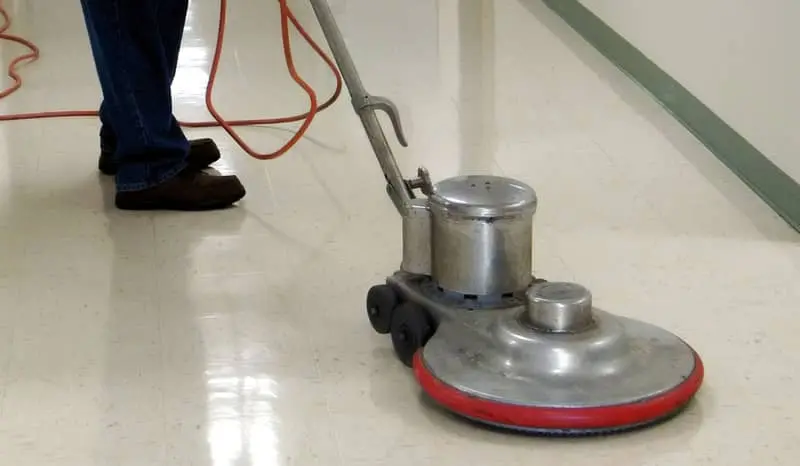 Cleaning employee buffering a hallway