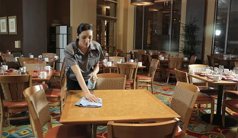Restaurant cleaner wiping down tables in the lobby