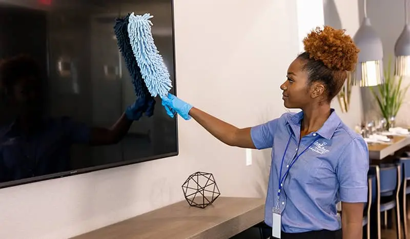 Janitor dusting off monitor screens in the lobby
