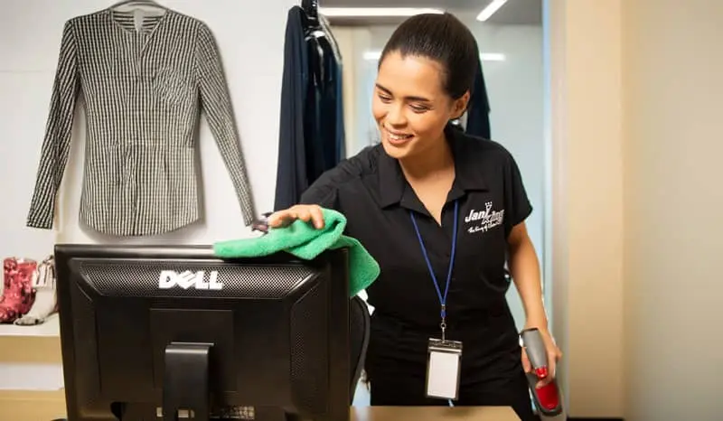 Jani-King employee wiping down a computer monitor