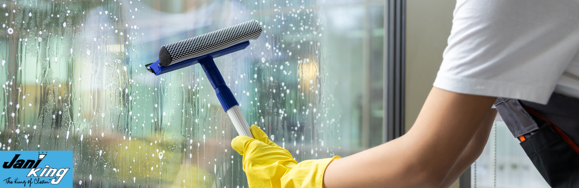 Jani-King employee cleaning a window.