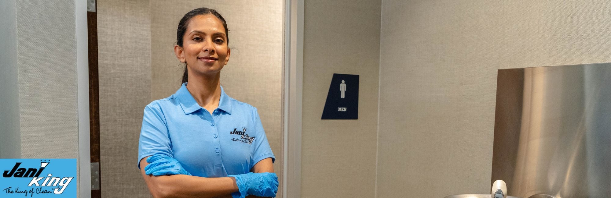 Jani-King employee posing next to the clean school bathroom.