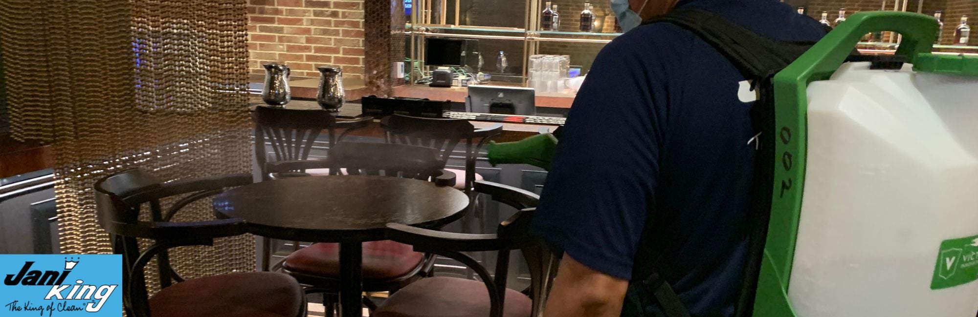 Jani-King employee cleaning a restaurant table.